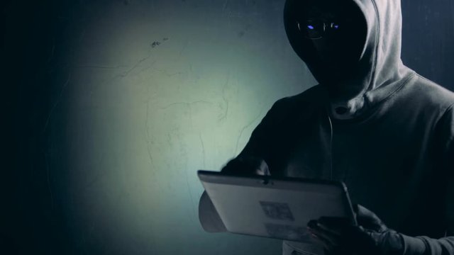 Hacker works with tablet while cracking system, close up.