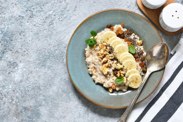 Breakfast: oatmeal, banana, nuts, chia seeds on the kitchen table. View from above.