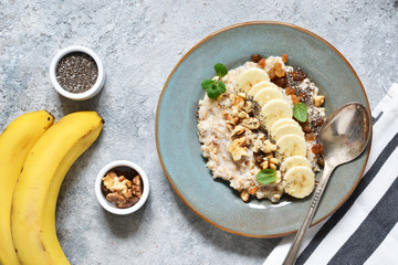 Breakfast: oatmeal, banana, nuts, chia seeds on the kitchen table. View from above.