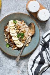 Breakfast: oatmeal, banana, nuts, chia seeds on the kitchen table. View from above.