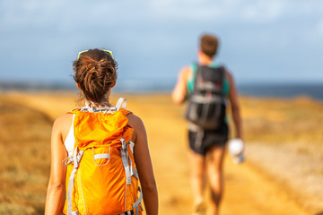 Hiking people couple walking with backpacks on hike trip trail in mountain nature outdoors....