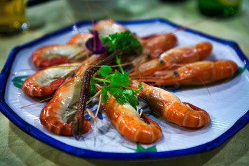  Boiled red shrimp served on a white dish with blue trim. 