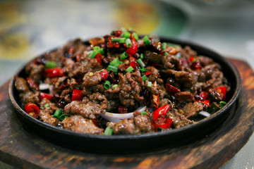  Chinese dish of fried beef in a sauce with red pepper and green onions, served on a cast iron...