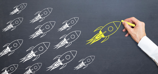 business man is drawing yellow rocket on blackboard with chalk. rising concept