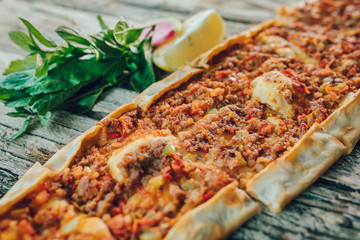 Traditional Turkish Pide or Pita pastry product on wooden table in turkish restaurant.