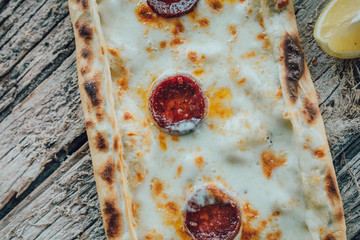 Traditional Turkish Pide or Pita pastry product on wooden table in turkish restaurant.
