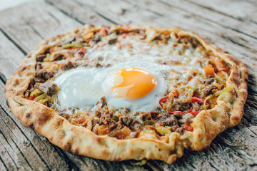 Traditional Turkish Pide or Pita pastry product on wooden table in turkish restaurant.