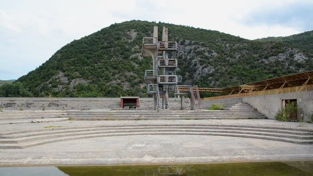 Abandoned and forgotten swimming pool. Diving board. Old, empty and falling apart pool in Bosnia and Herzegovina. Closed, neglect ruined and dangerous place.  