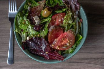 Healthy veggie bowl with green salad, tomatoes, green and black olives, feta cheese. 