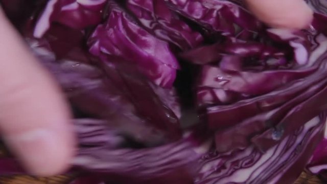 Slices of red cabbage is checked by hand on a wood kitchen table. Beautiful patterns on the cut slice. Healthy food. Vegetable diet. Vegetarianism