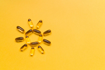 Close up capsules of fish fat oil in the sun shape, omega 3, vitamin e on the yellow background. Healthy food diet. Nutritional supplement - obrazy, fototapety, plakaty