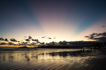 Sunset in Santos with pink rays and crescent moon