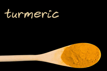 turmeric on wooden spoon isolated on black background