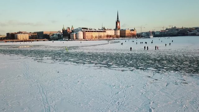 Drone flies low over the water towards Vadstena Slott, a Scandinavian palace castle with a moat by V&auml;ttern Lake.