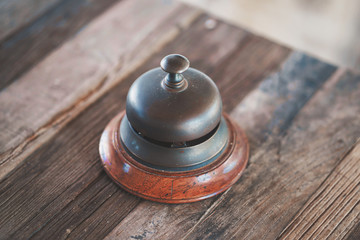 Vintage hotel reception service desk bell on wooden table. Old retro style.