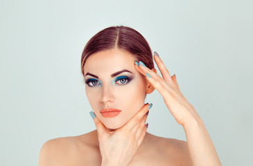 Sexy and sassy. Beautiful woman touching face with hands showing perfect makeup and soft skin,...