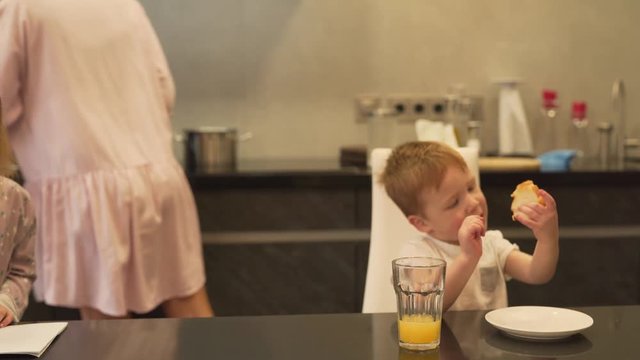 The mother talks with her son and checks whether he eats. In a meantime, she cooks together with her eldest daughter at the back.