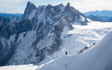 A snowy mountain view from Aiguille du Midi with two people hiking