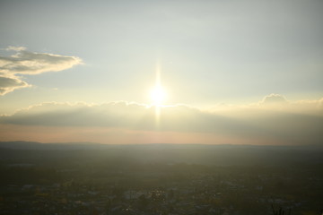 pre-sunset sunlight in the form of a bright star over the town to the mountains