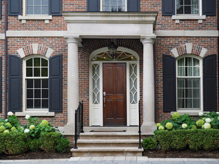 elegant wooden front door of house with columns and shutters