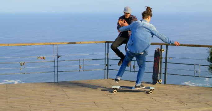 Rear view of young male skateboarder riding on skateboard at observation point 4k