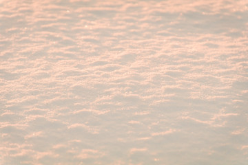 Snow at sunrise reflects a coral tone for winter background