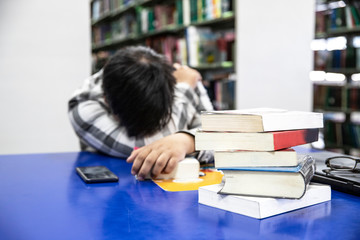 Close up books burry Overworked male  student sleeping on the desk on his notes  at the library. - Image © aumnat