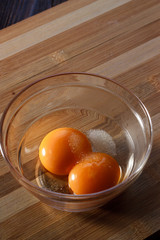 egg yolks in a glass mixing bowl. wooden board.