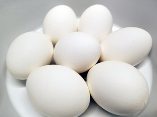 Seven jumbo hard boiled eggs sitting on a small white plate