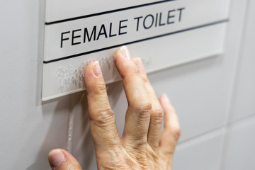 Finger reading braille tactile on toilet signage