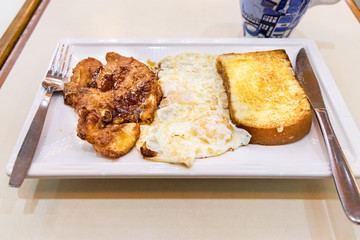 Simple pork chop, fried eggs, bread breakfast in Hong Kong