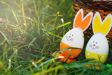 Handmade funny creative eggs lies on green grass next to natural basket at sunny spring day. Happy...