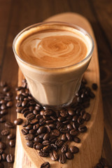 Coffee Latte Flat white in a glass with coffe beans spread out on a wooden table.