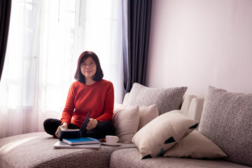 Fototapeta premium Beautiful girl at home sitting on the couch, reading a book.