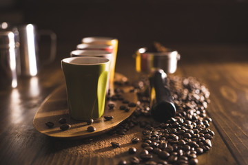 Coffee beans, tamper, portafilter, grinds and espresso cups on a wooden surface.