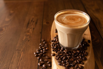 Coffee Latte Flat white in a glass with coffe beans spread out on a wooden table.