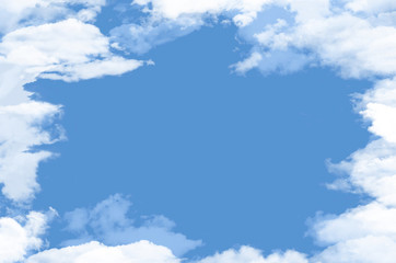 White fluffy clouds surround an opening that reveals clear blue sky where graphic elements or text may be placed.