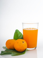 Glass with orange juice and fruits with green leaves