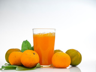 Glass with orange juice and fruits with green leaves