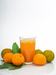 Glass with orange juice and fruits with green leaves