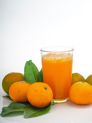 Glass with orange juice and fruits with green leaves