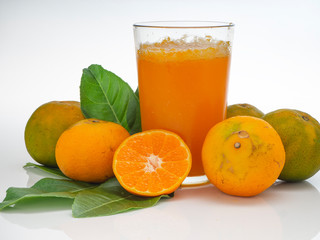 Glass with orange juice and fruits with green leaves