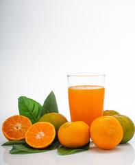Glass with orange juice and fruits with green leaves