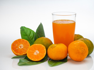 Glass with orange juice and fruits with green leaves