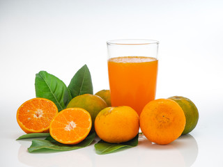 Glass with orange juice and fruits with green leaves
