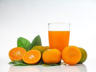 Glass with orange juice and fruits with green leaves