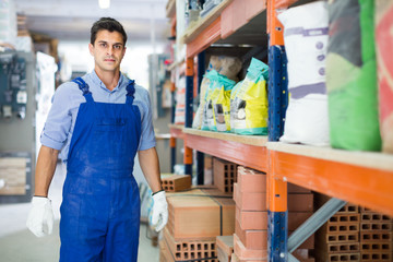 Portrait of young man in uniform on his workplace in building store.