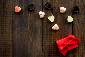 Gift for Valentine's day. Gift box with text I love you and heart-shaped sweets on dark wooden background top view copy space