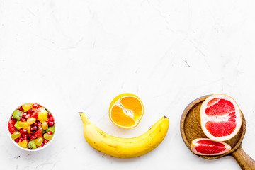 Healthy diet concept. Fruit salad near fresh fruits on white background top view copy space