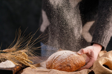 Homemade rye bread and spikelets close-up on a dark background. The concept of healthy food and traditional bakery.